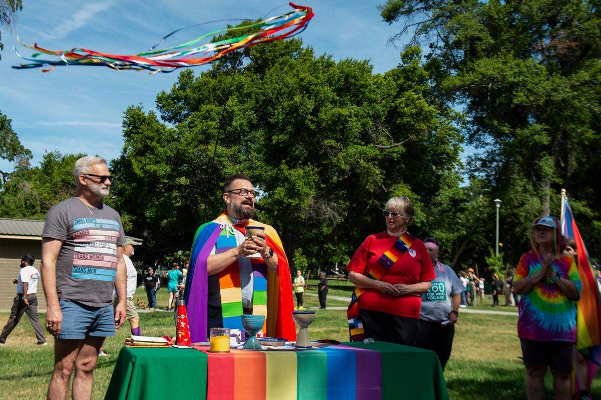 Dean Matthew Woodward, of Trinity Cathedral Church of Sacramento, performs communion before the Sacramento Pride March and Parade on Sunday, June 11, 2023, in Southside Park. Woodward said that many parade-goers aren’t comfortable with religion, sometimes because of negative past experiences. “It will take a long time to change that perspective, but I believe in the fullness of time we will if we continue being consistent, present and showing up and sharing the love of God in an inclusive way for the LGBTQ community.”