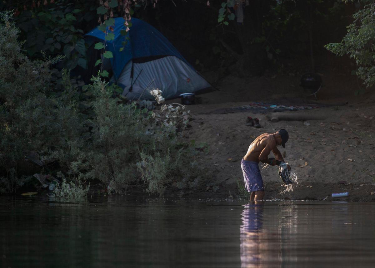 A man washes clothes in the American River in Sacramento on Aug. 28.
