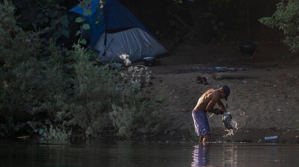 A man washes clothes in the American River in Sacramento in 2019.