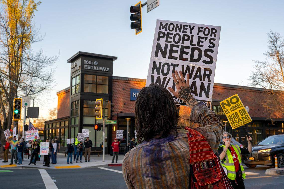 Demonstrators hold signs at the intersection of Land Park Drive and Broadway in Sacramento on Monday while demonstrating against the U.S.-Israel war with Iran.