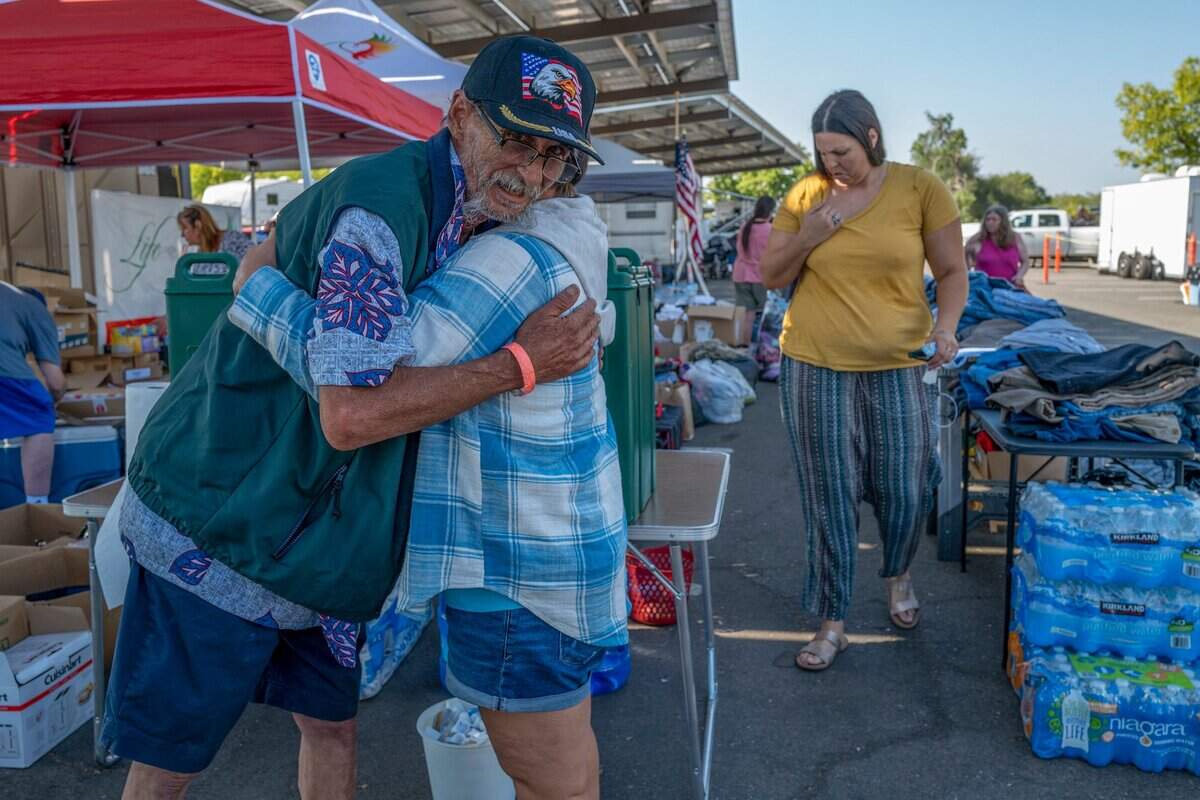 Derek Jones, an evacuee from Foresthill, hugs Lynda Hogge of Woodland after she dropped off supplies for Mosquito Fire evacuees at Sierra College on Thursday in Rocklin. Hogge says she has survived four house fires and understands what the fire victims are going through.