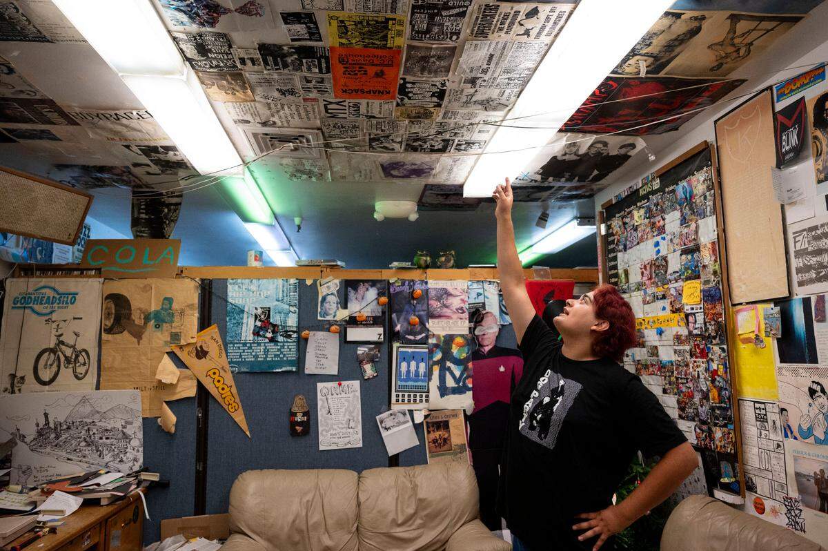 Izzy Barney, one of the event coordinators at KDVS radio station at UC Davis, points out some vintage concert posters that line the ceiling of the lounge last month. Freeborn Hall is being demolished for safety purposes and the station will have to relocate from the basement where they’ve broadcast from for 60 years.