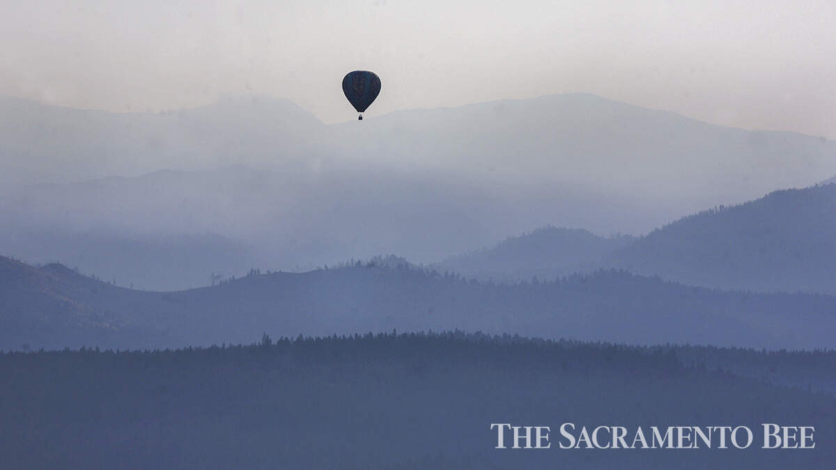 A hot air balloon flies through the valley in 2007 near Truckee with the Sierra Nevada in the background as smoke from the Moonlight fire in Plumas County lingers in the early morning air.