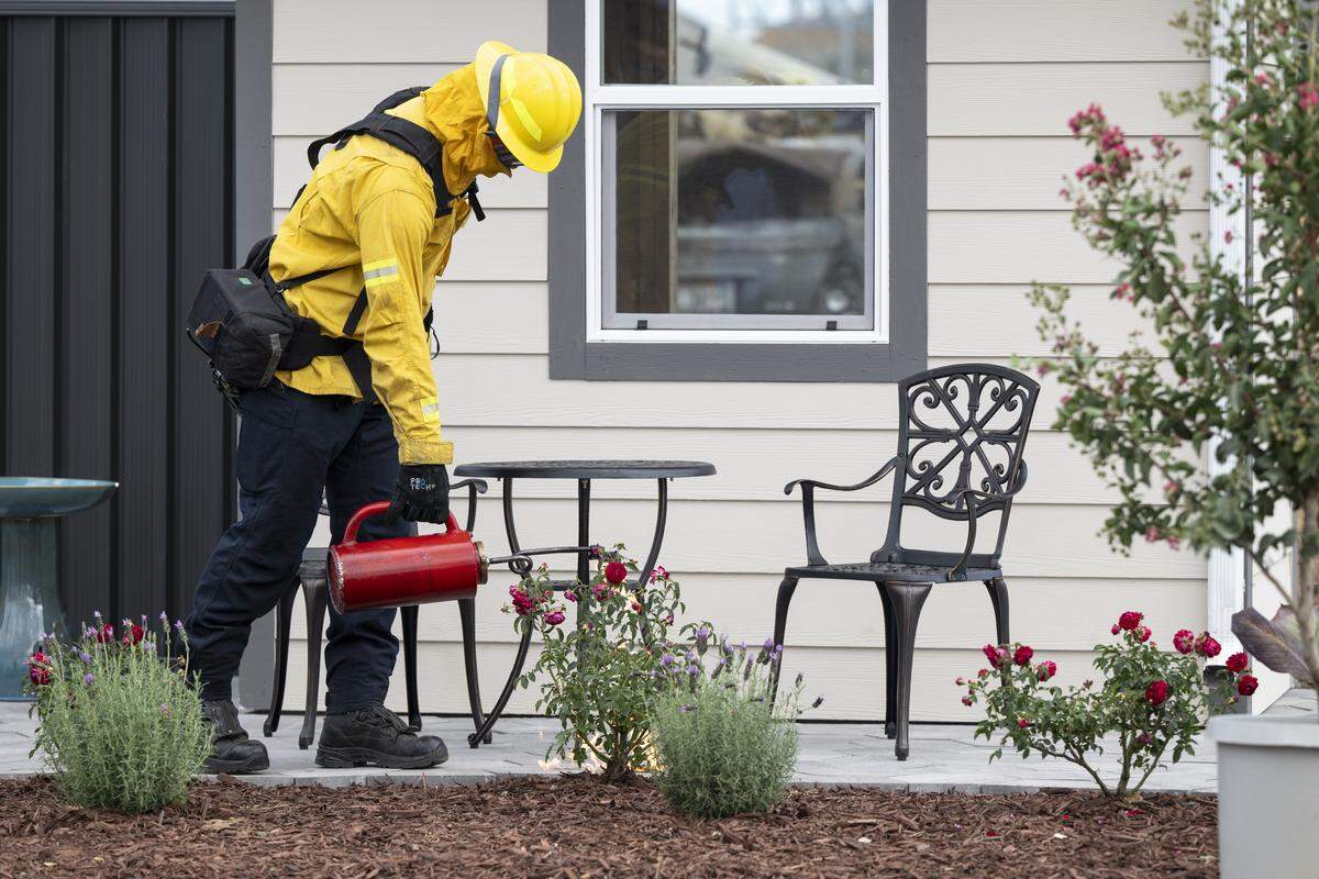 Firefighters use drip torches to ignite mulch and plants near mock houses during a burn demonstration at the Sacramento City Fire Training Facility at McClellan Airfield on Wednesday. Cal Fire and IBHS hosted the burn to demonstrate the impact of proposed Zone Zero regulations in a wild fire scenario.
