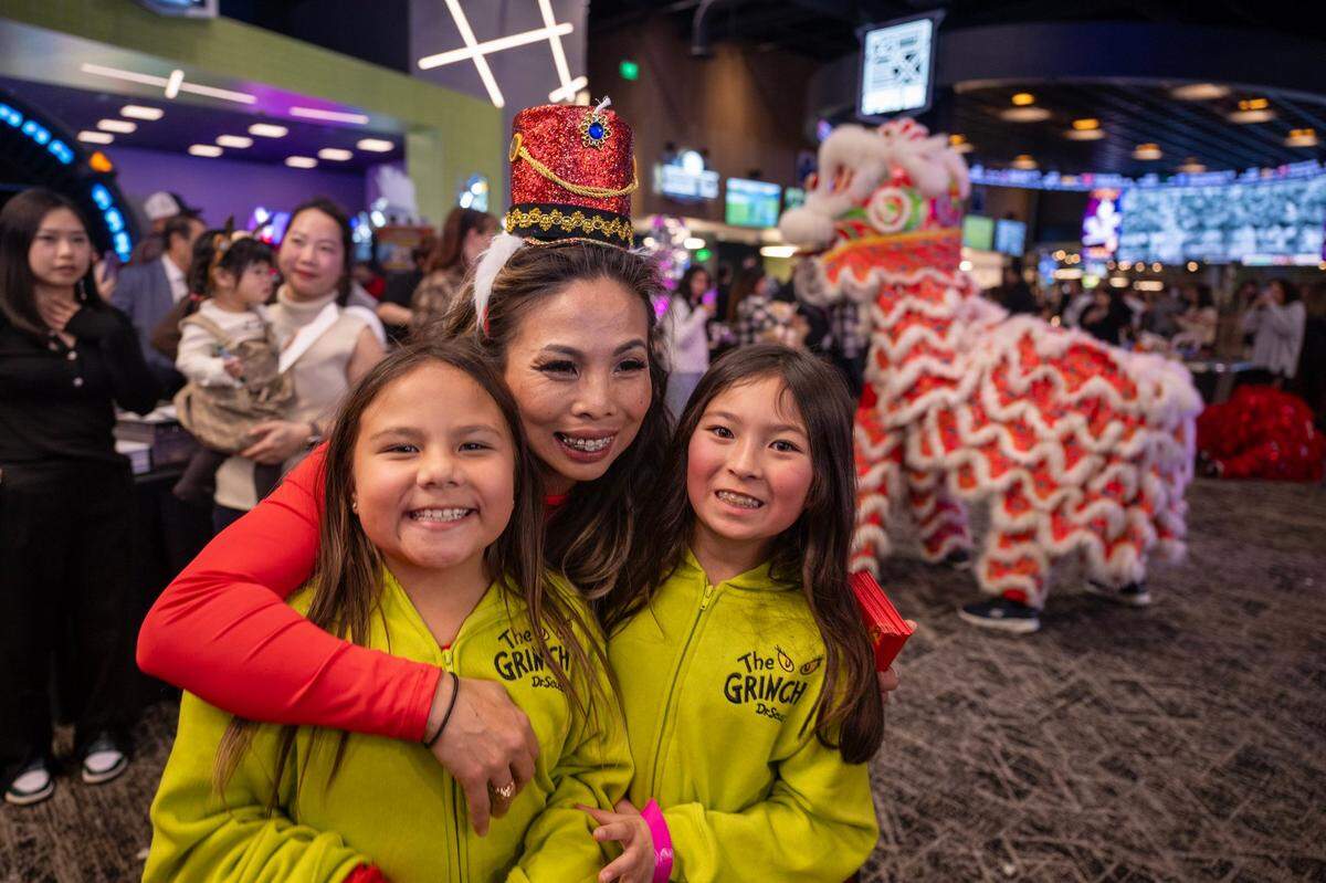 Anh Phoong embraces her daughter Annie, left, and Annie’s friend Penny during the lion dance at Phoong’s annual Christmas party earlier this month at The Apex at Red Hawk casino.