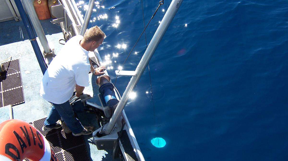 Tahoe Environmental Research Center boat captain Brant Allen lowers a Secchi disk from the research vessel into Lake Tahoe in 2018. The disk has been used for more than 50 years to measure water clarity at the lake.