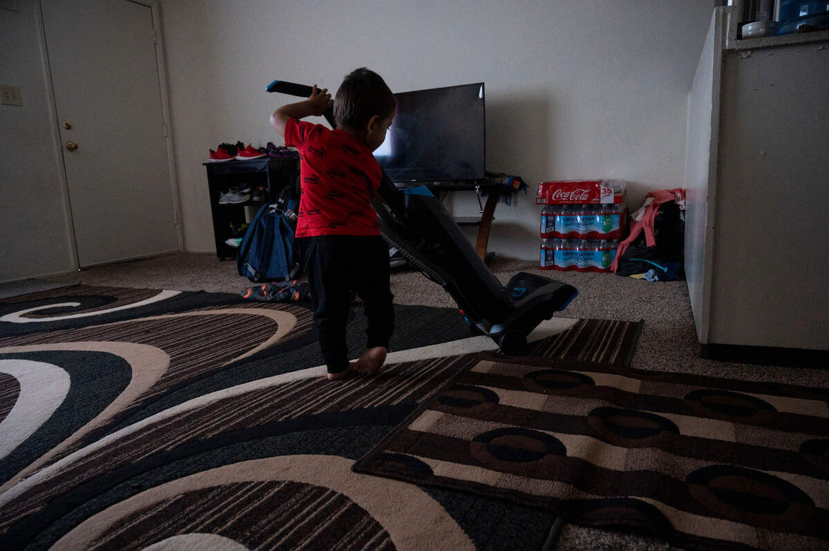 A carefree 2-year-old Afghan boy is content to play in the living room with an upright vacuum cleaner on Nov. 24.