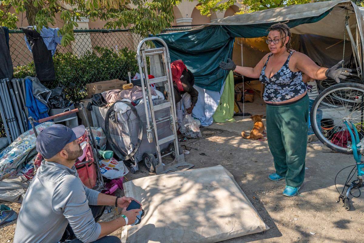 Christopher Bell, left, with the City of Sacramento Department of Community Response, listens to the plight of a homeless resident who called herself Lilith Whyte, 24, at a homeless encampment across the street from Garden Valley Elementary School in South Natomas on Friday, Sept. 16, 2022. Bell is part of a team that answers 311 calls.