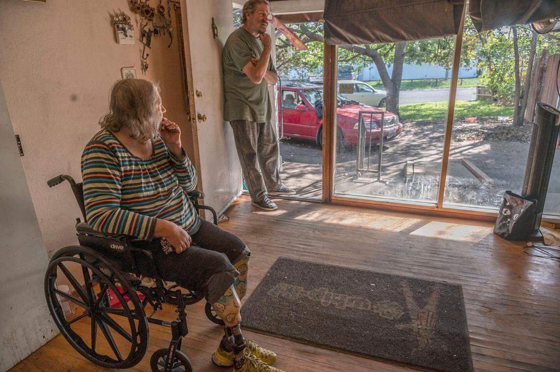 Linda Siegrist, 67, and her husband Bruce, 66, look out the front window of their Sacramento home on Thursday, Nov. 4, 2021. At the city’s request, the property was placed into receivership because of code violations. The court-appointed receiver wanted to replace the window. “I thought there is nothing wrong with it,” Linda said. “It’s not broken.”