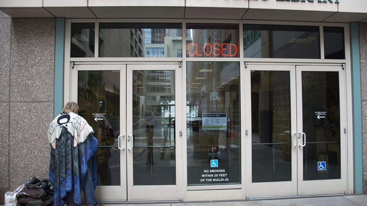 A homeless man waits for the Central Library to open. Librarians and other staff members have received training to understand and deal with homeless people, as many use public restrooms inside every day.