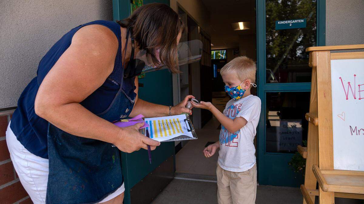 Kindergarten teacher Lynn Scales squirts hand sanitizer on Maddox Korb, 5, as he enters her classroom during the first day of school at Rescue Elementary School on Monday, Aug. 17, 2020. The school is able to open for in-class instruction because El Dorado County is not on the state’s coronavirus watchlist.