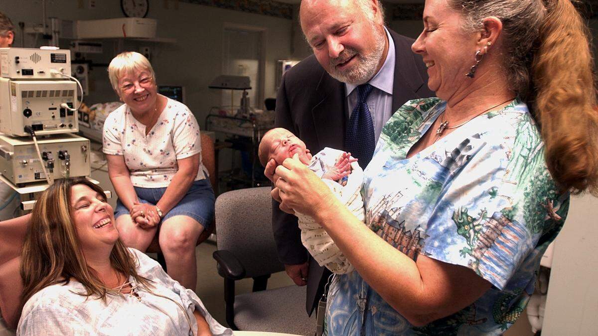 First 5 California commission chair Rob Reiner looks at triplet Wyatt Evans, held by nurse Penny Pell, as mother Lorna Richardson-Evans, left, smiles at Kaiser Hospital in Sacramento on June 29, 2004. 
