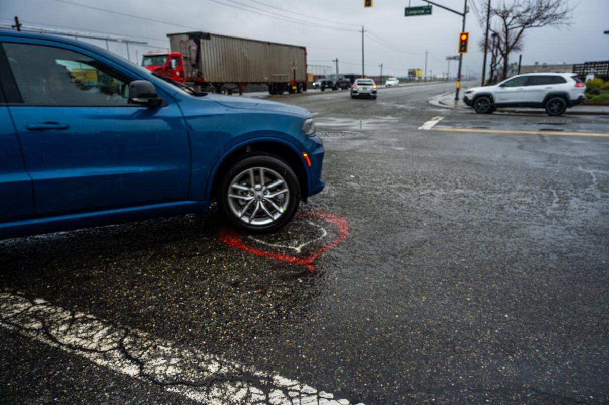 A car drives over a heart earlier this month that Phillip Minton painted for his partner Wendy Connell at the intersection of Roseville Road and Longview Drive in North Highlands, where she was fatally hit by a truck in January.
