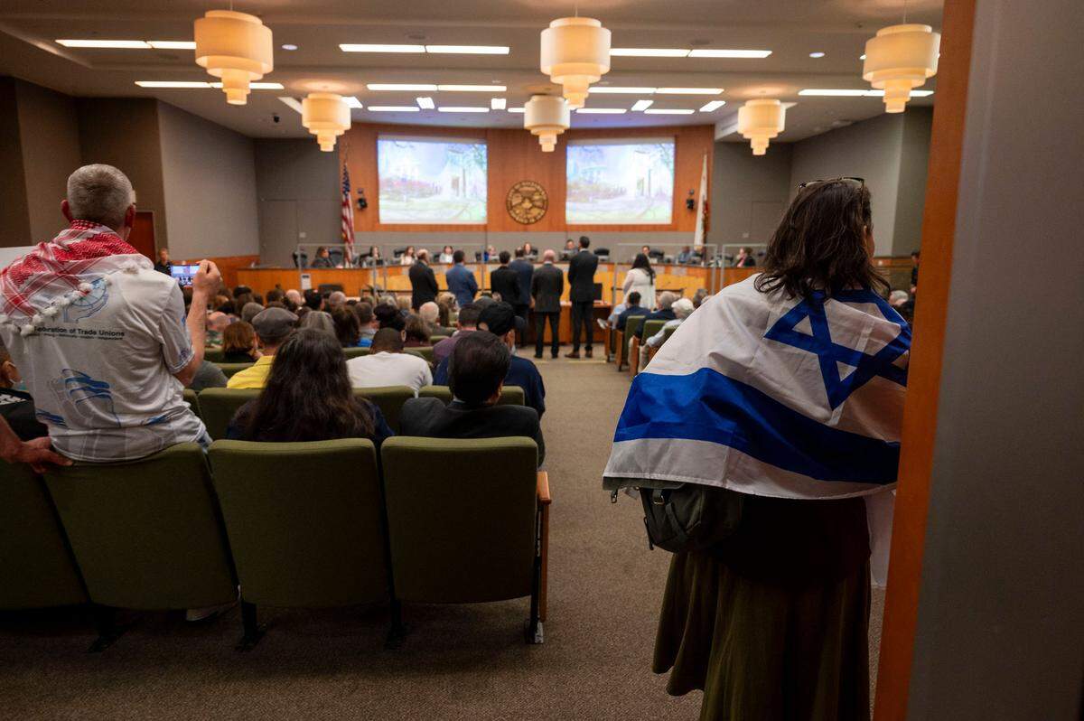 A woman wearing an Israeli flag enters the Sacramento City Council meeting on Tuesday. The city council approved a Gaza cease-fire resolution proposed by leaders in Sacramento’s Jewish and Muslim communities.