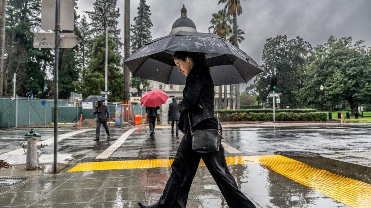 McKinley Thompson-Morley walks to work in the rain on Wednesday, Jan. 24, 2024 in downtown Sacramento near the state Capitol.