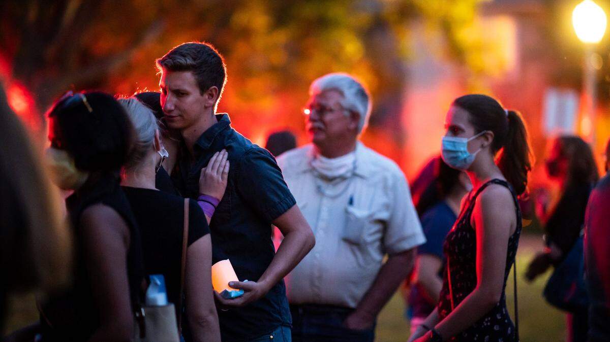Carson Tibbitts, left, is embraced by people attending a vigil for his aunt Kate Tibbitts at Plaza Cervantes Park on Thursday in Sacramento’s Land Park neighborhood. Casey, seen in front of a glow from several ambulances that encircled the park in honor, spoke during the vigil about watching a 49ers game with his aunt.