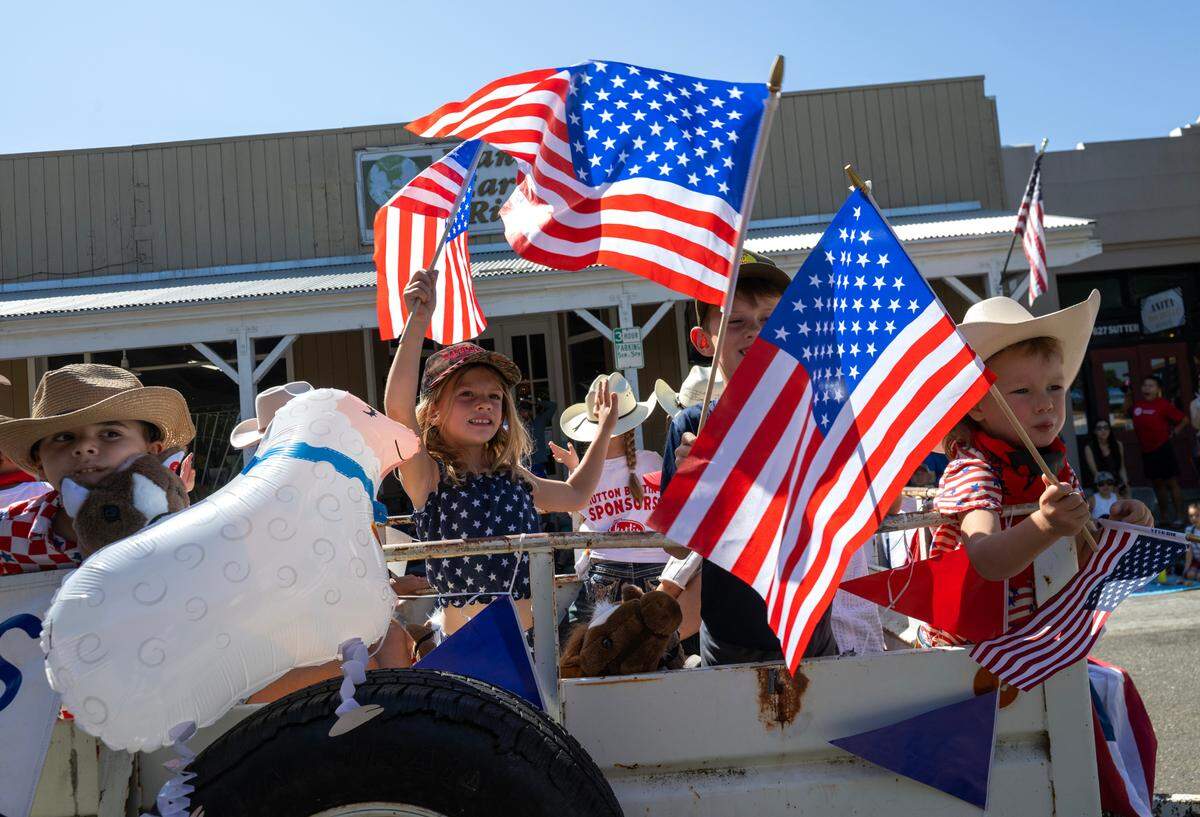 Mutton buster participants wave American flags as they ride down Sutter Street at the Folsom Historic Parade on Saturday in Folsom.