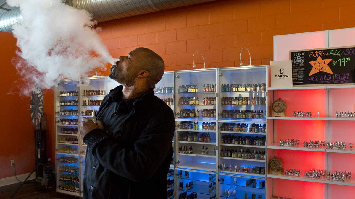 Mario Weaks, a sales associate at The Vapor Spot in midtown Sacramento, exhales from his e-cigarette in 2015. Vape shop owners say a proposed citywide ban on flavored tobacco products would devastate their business.