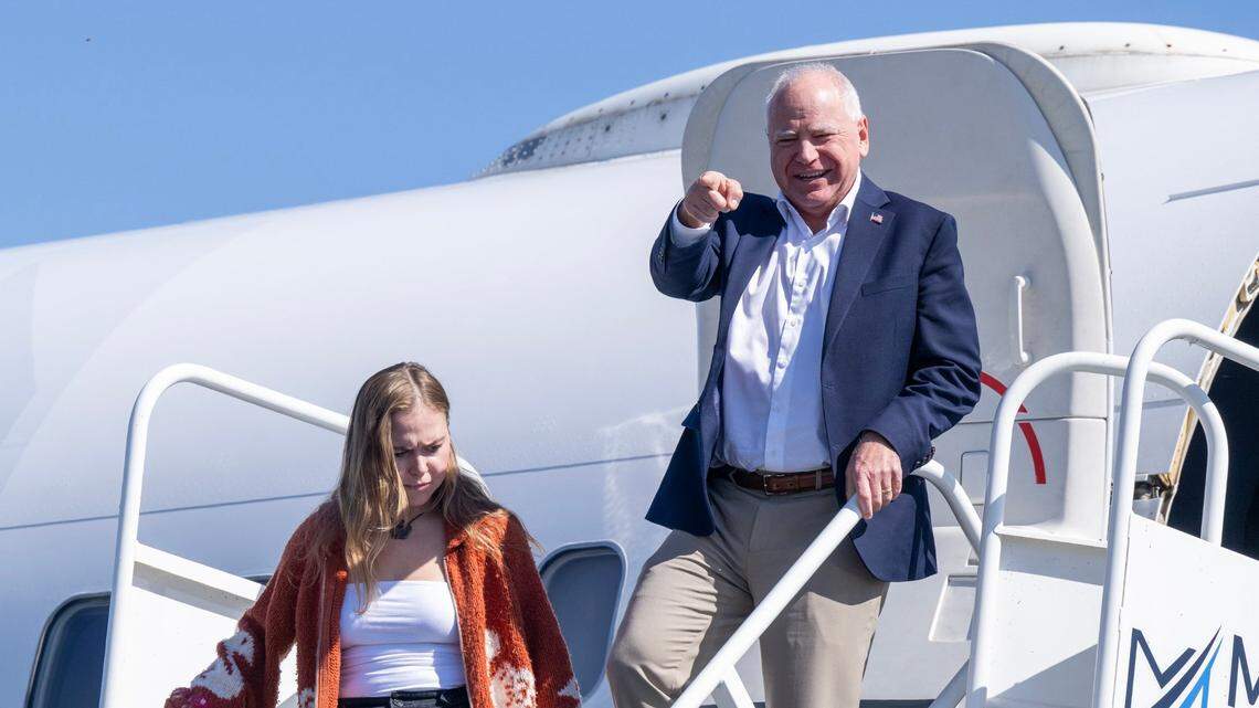 Democratic vice presidential candidate Tim Walz, governor of Minnesota, points to local dignitaries as he departs a plane at Sacramento International Airport with daughter Hope Walz on Tuesday, Oct. 8, 2024. Walz is visiting the city on a fundraising trip.