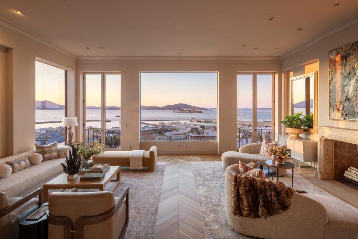 The home’s panoramic view living room is designed stage the bay — water and sky framed elegantly.