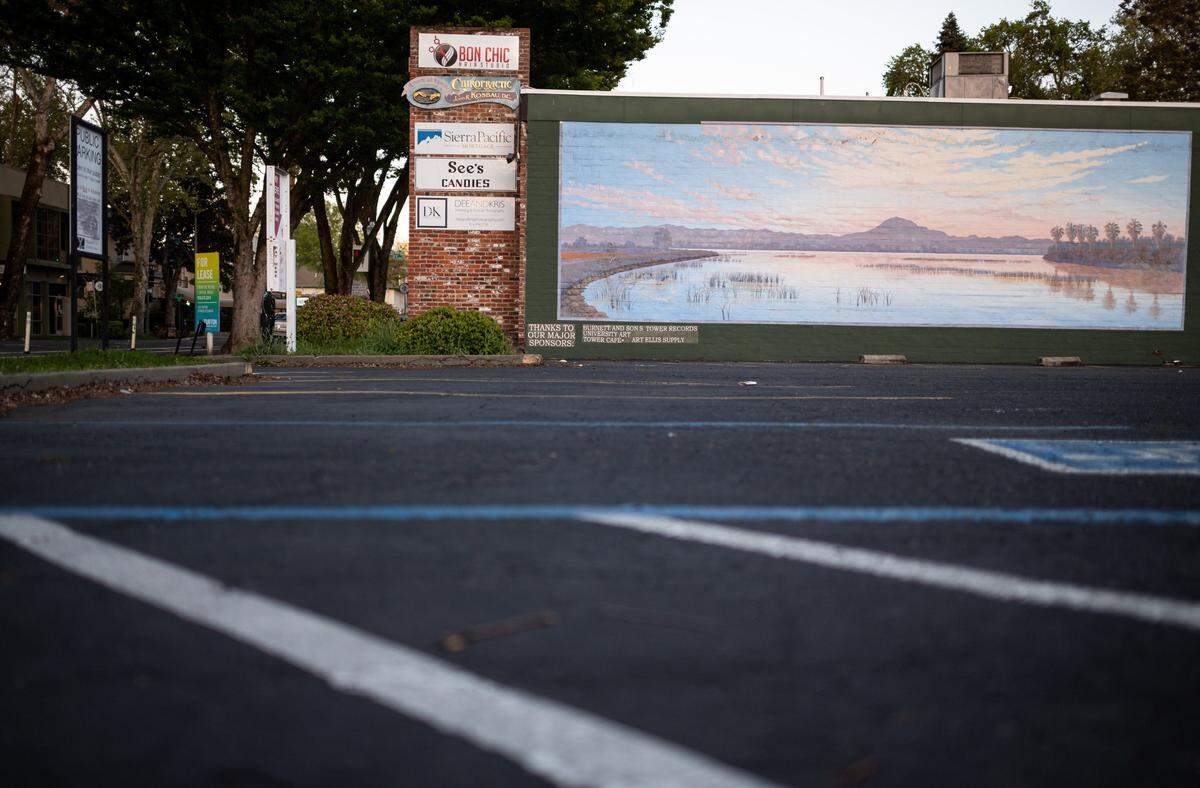 A mural overlooks an empty parking lot on the 2200 block of J Street in Sacramento on April 11. Business in the surrounding midtown neighborhood have ground to a halt amid the new coronavirus.