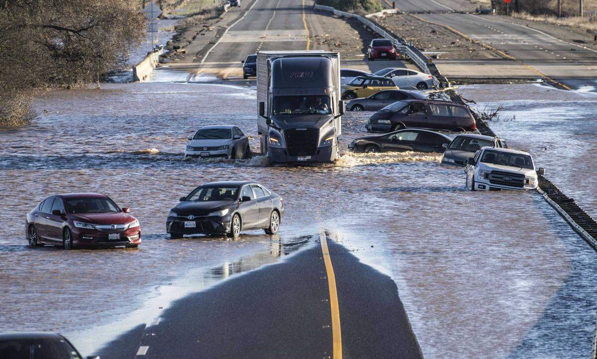 A semi-truck drives on Highway 99 on Jan. 1 past abandoned cars that were stranded amid flooding Dillard Road in south Sacramento County. NOAA has warned of a “historically strong” El NiÃ±o through January but, unlike last year’s drenching holiday storms, California’s wet season has been notably dry.