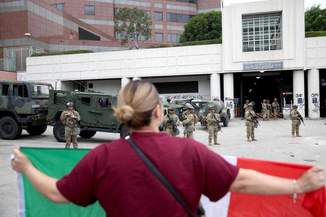 Elizabeth Torres holds a Mexican flag while facing California National Guard soldiers at the Metropolitan Detention Center in Los Angeles on Sunday, June 8, 2025. Protests erupted after federal immigration raids across Southern California.
