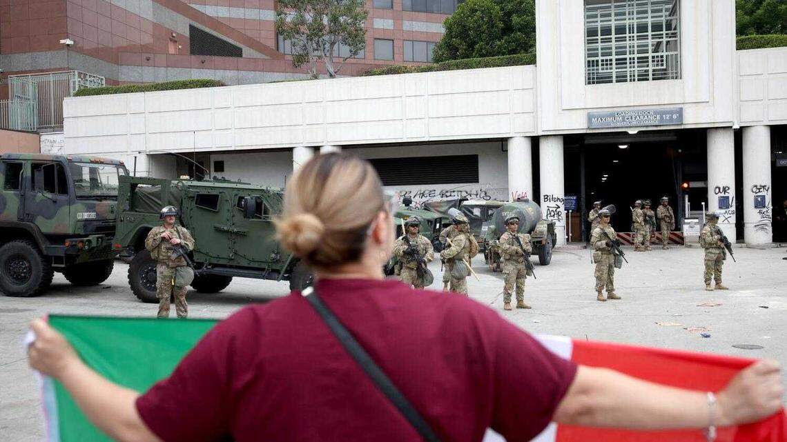 Elizabeth Torres holds a Mexican flag while facing California National Guard soldiers at the Metropolitan Detention Center in Los Angeles on Sunday, June 8, 2025.