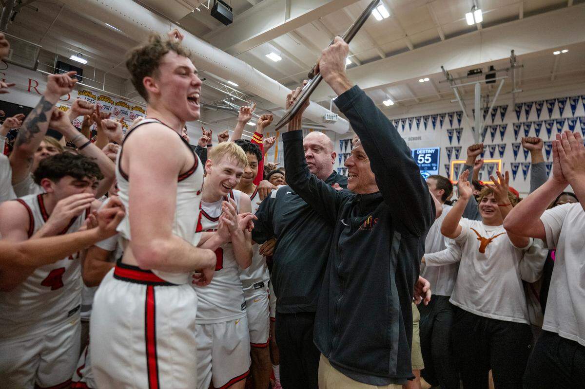 Jesuit Marauders head coach Tim Kelly holds up the CIF Northern California Division II boys basketball championship trophy with his team following the 65-55 victory over the Destiny Christian Lions in Carmichael.