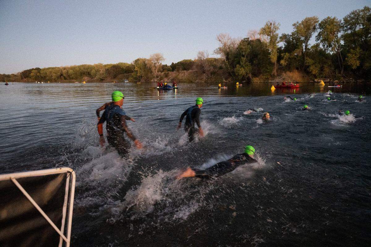 The first wave of swimmers enters the American River during the Ironman California triathlon in Sacramento on Sunday, Oct. 23, 2022.