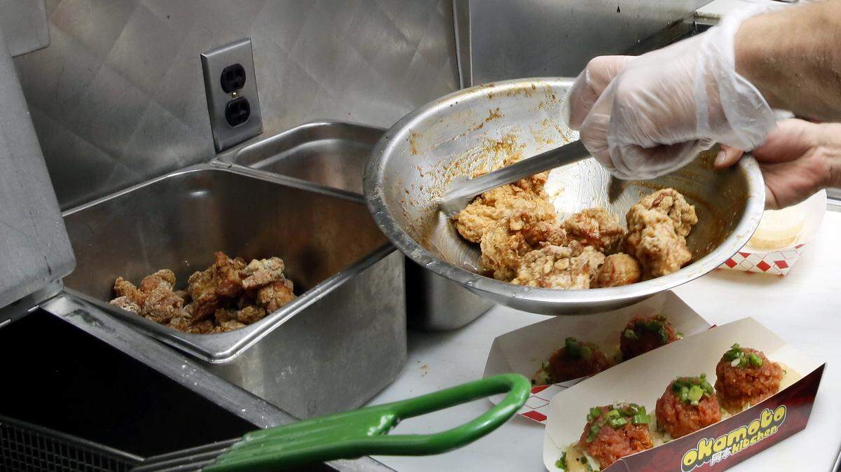 In this Friday, June 8, 2018, photo chef Raimundo Bobadilla prepares a plate of Japanese Fried Chicken J.F.C. plate at the Japanese food truck Okamoto Kitchen in Beverly Hills, Calif. Rather than sushi and tempura, they serve meat, fish and sandwiches using traditional Japanese flavors like ponzu.
