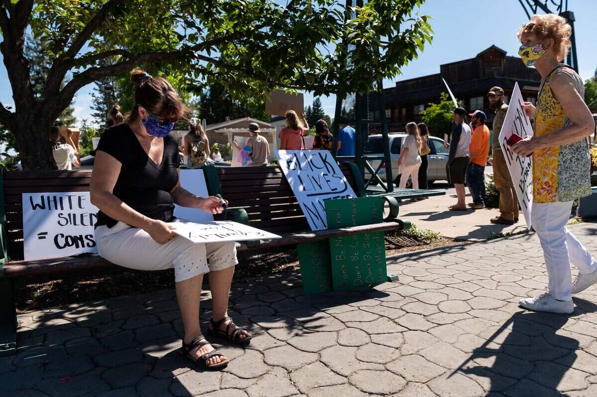Beth Miller, left, of Colfax, writes out a sign as she joins protesters rallying against racial injustice in Colfax on Wednesday.