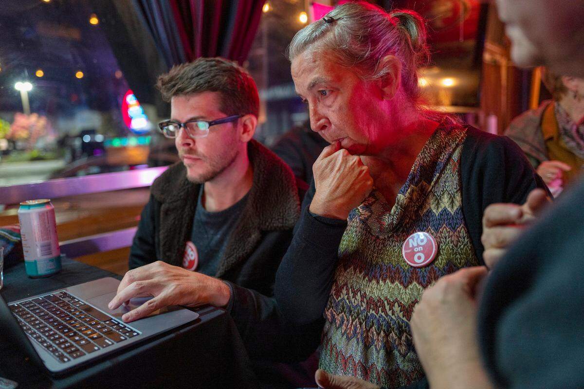 Dave Kempa, communication director for Neighbors Against Measure O, left, and Tamie Dramer, executive director of Organize Sacramento, right, look over early results at a ‘No on Measure O’ party at Clubhouse 56 in East Sacramento on Tuesday, Nov. 8, 2022. The measure, which would empower Sacramento officials to clear homeless tents more often, was leading in early returns.