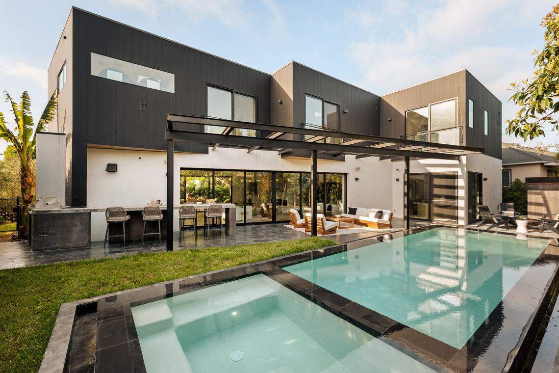 The home’s outdoor amenties include an infinity-edge pool with jetted spa, a sleek outdoor BBQ kitchen with built-in dining space, and a modern fire pit set.