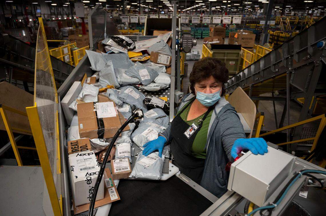 Postal worker Svetlana Plugovoy scans packages on a small parcel sorting system at the Sacramento Processing and Distribution Center on Tuesday, Nov. 2, 2021. The postal service is projecting between 850 and 950 million packages will be delivered this holiday season and more than 12 billion letters, cards and packages will be processed and delivered.