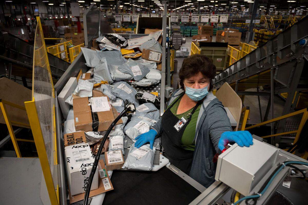 Postal worker Svetlana Plugovoy scans packages on a small parcel sorting system at the Sacramento Processing and Distribution Center on Tuesday, Nov. 2, 2021.