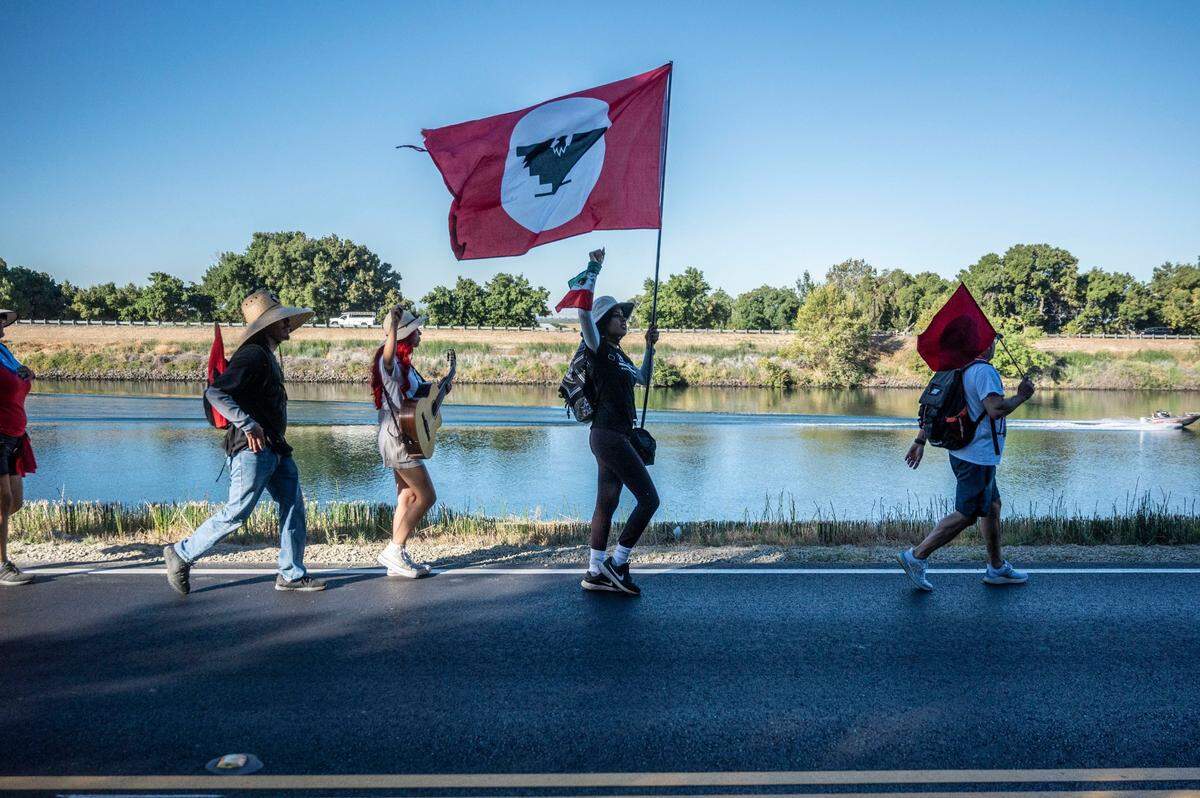 Flor Martinez Zaragoza, center, of San Jose, holds her fist in the air while holding the United Farm Workers’ trademark red-and-black flag as marchers make their way along the Sacramento River near Walnut Grove on Wednesday.