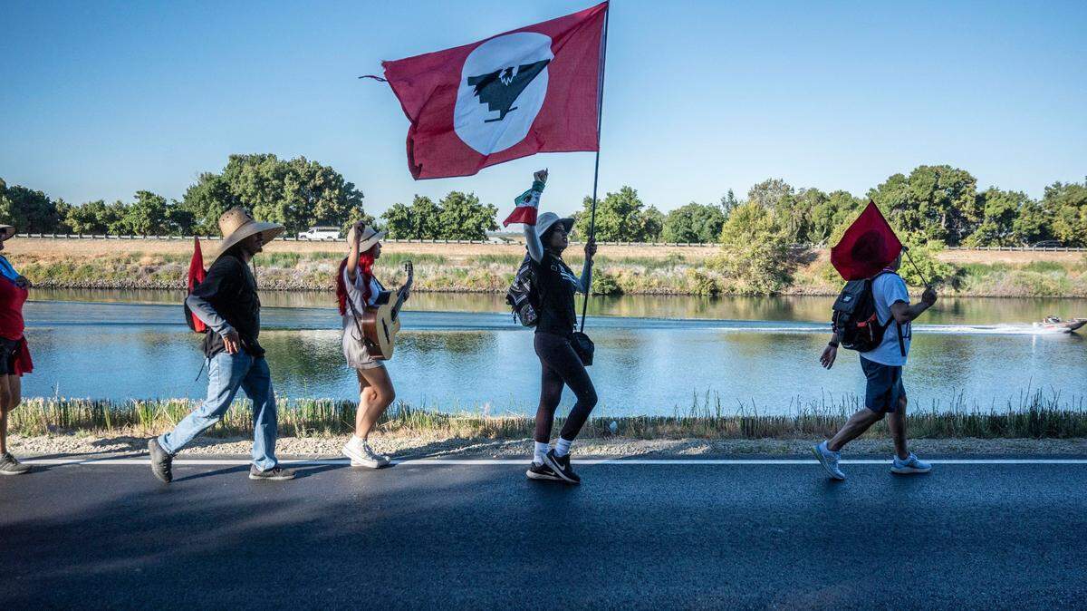 Flor Martinez Zaragoza, center, of San Jose, raises her fist in the air while holding a flag as supporters and members of the United Farm Workers union make their way to Sacramento on Aug. 24 in an effort to urge Gov. Gavin Newsom to sign a bill that would give farmworkers the ability to vote from home to unionize.