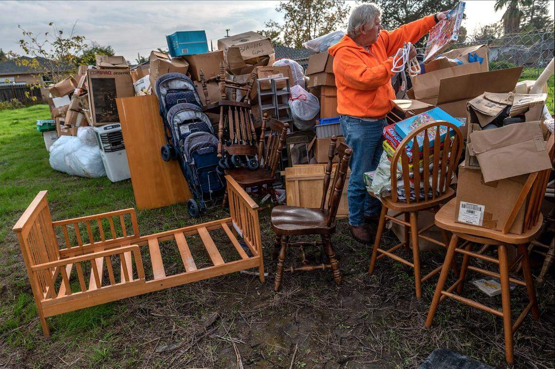 Mark Melton holds a children’s game as he sorts through items, including many family mementos from relatives who had recently died, in November. The items had been stored in two trailers on his property when crews for a court-appointed receiver dragged away one trailer and left the boxes it held in his backyard. He wasn’t sure how he was going to store the items and was afraid they would get damaged in the rain.