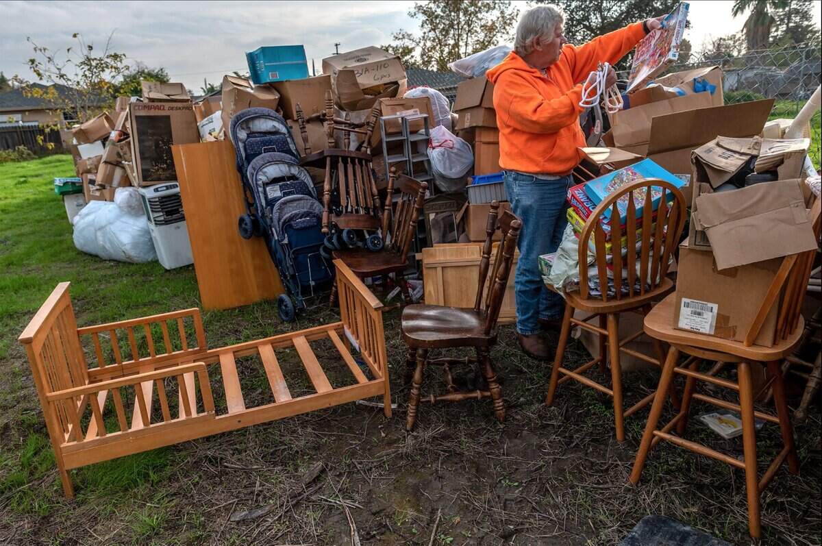 Mark Melton holds a children’s game as he sorts through items, including many family mementos from relatives who had recently died, in November. The items had been stored in two trailers on his property when crews for a court-appointed receiver dragged away one trailer and left the boxes it held in his backyard. He wasn’t sure how he was going to store the items and was afraid they would get damaged in the rain.