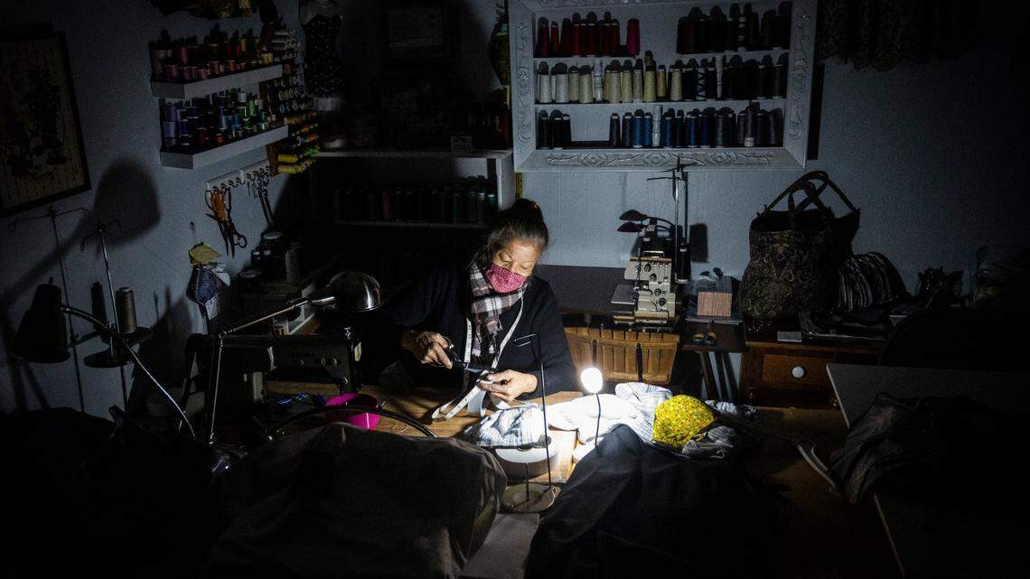 Rose Turner of Rose Alteration cuts elastic using a battery powered light during a power outage in her shop in downtown Placerville on Monday, Oct. 26, 2020. PG&E shut off power to 355,000 homes and businesses as part of a public safety power shutoff that started Sunday night because of a severe windstorm.