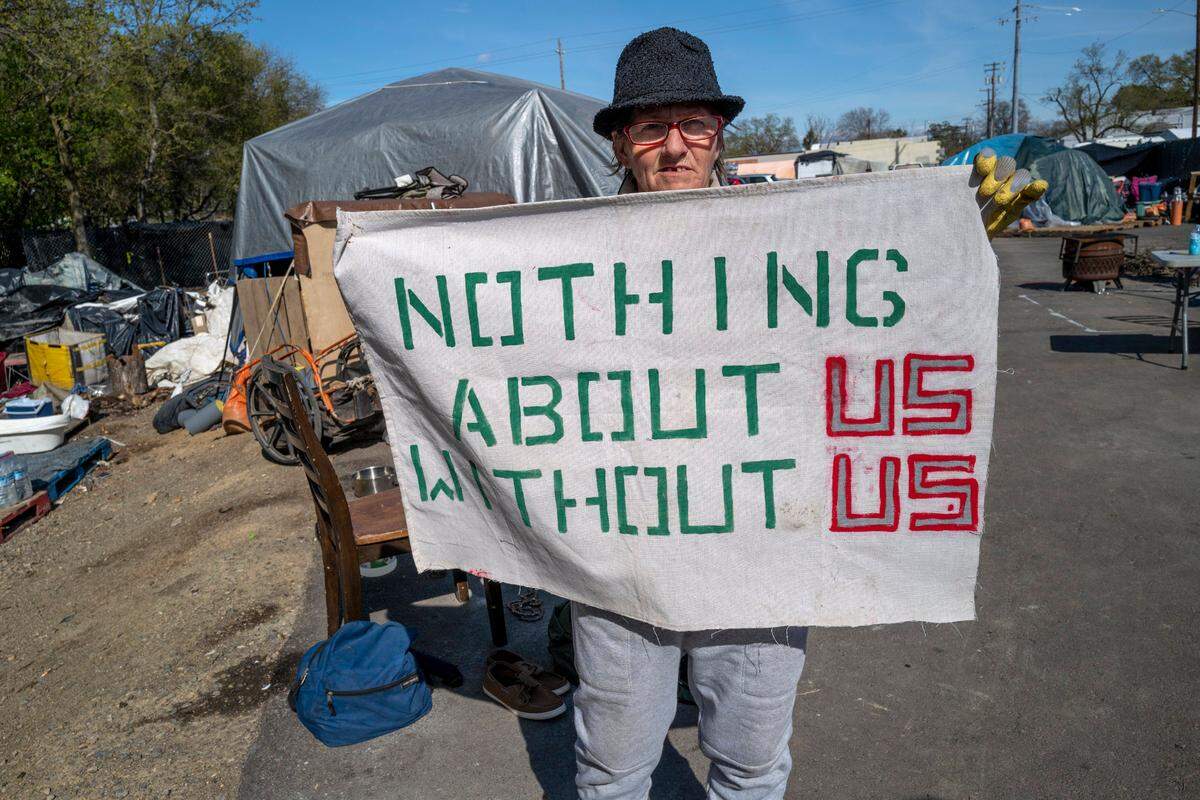 Joyce Williams proudly shows off a sign on Friday representing the solidarity of the residents of Camp Resolution, a self-governing homeless encampment in North Sacramento. She and her partner Sharon Jones, along with other residents, have rallied together to take care of Holly Porter.