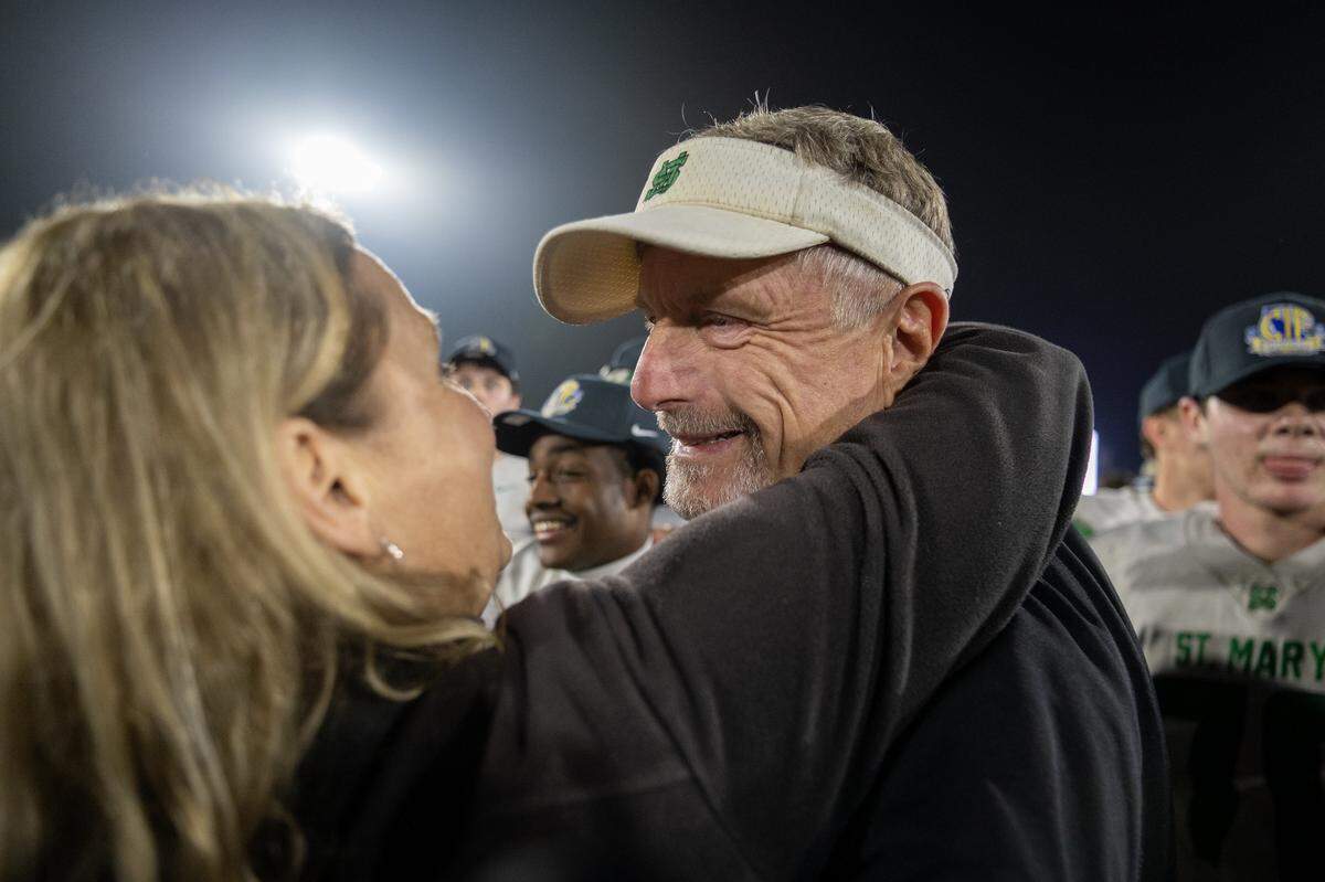 St. Mary’s Rams head coach Tony Franks is embraced by his wife Christina following the team’s victory over Bakersfield Christian in the CIF Division 2–AA State Championship football game at Saddleback College in Mission Viejo on Friday.