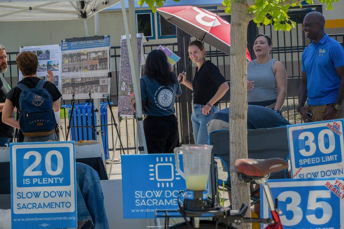 Makinzie Clark, senior planner for the Planning and Programs Division at the Sacramento County Department of Transportation, holds an umbrella resembling a stop sign while talking with students and nonprofits to raise awareness about slowing traffic on Dewey Drive in front of Del Campo High School in Carmichael on Thursday, May 7, 2026.