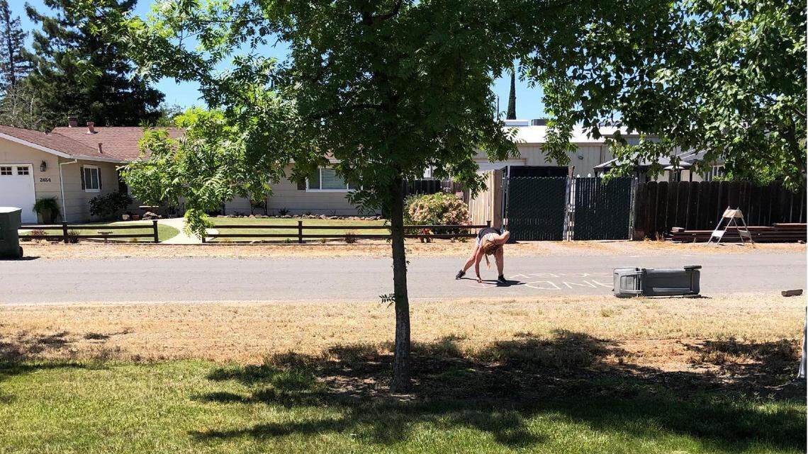 An unknown woman is seen allegedly writing a racial slur in chalk, with an arrow pointing toward the home of Rouble Claire in Sutter, Calif., on May 11, 2021. The woman also allegedly wrote the slur on Claire’s driveway.