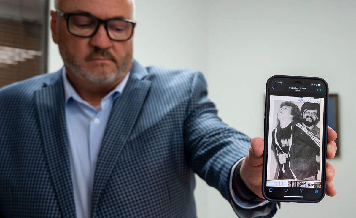 Scott Sorgea shows a copy of a yearbook photo on his phone, during an interview in March, showing former Capital Christian School coach and teacher Dave Arnold, right, holding one of his former students. Sorgea said during that time, Arnold routinely tied him up, blindfolded, gagged and subjected him to psychological abuse, eventually gratifying himself sexually. Sorgea is a member of a group of former students taking legal action.