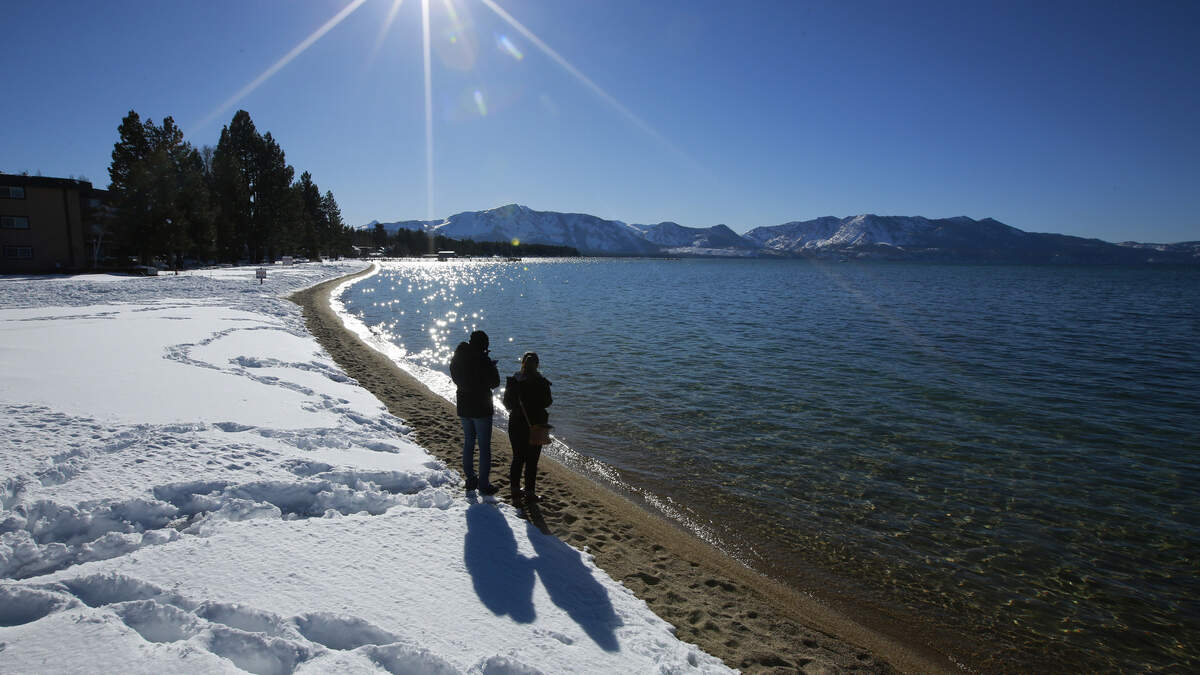 Sunlight shimmers off the snow and waters of Lake Tahoe in South Lake Tahoe. The coronavirus is hitting California’s most famous tourist sites hard.