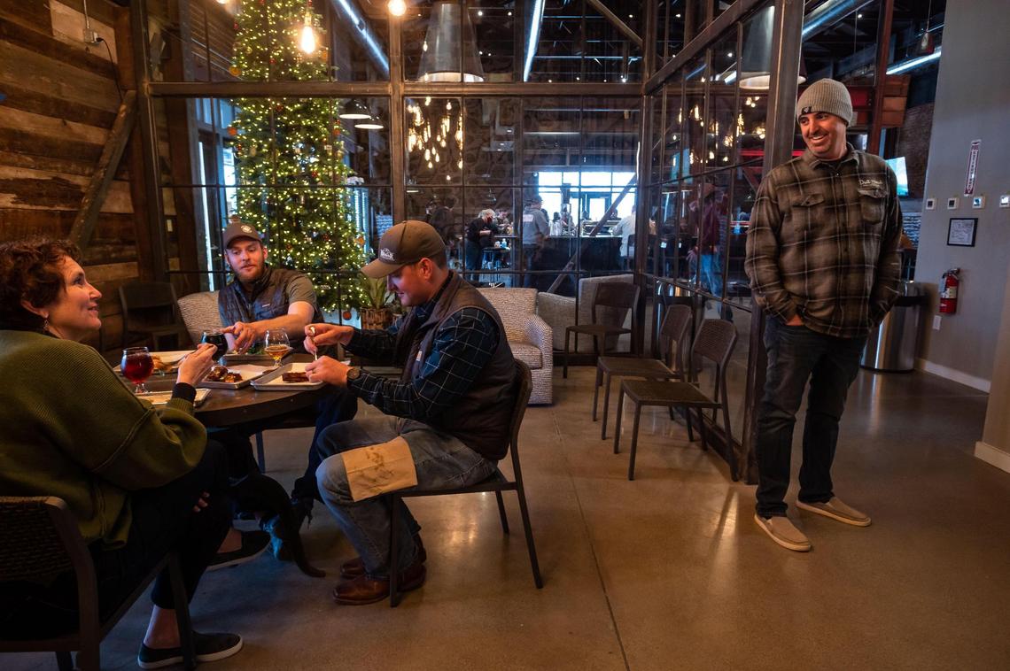 Dust Bowl Brewing Co. co-owner Brett Honoré, right, visits with Karen Tate, whose husband is co-owner Brett Tate, and brothers Lars and Colin Russell, all of Hilmar, in a room at Old Town Tap House on Saturday, Dec. 18, 2021, in Elk Grove.