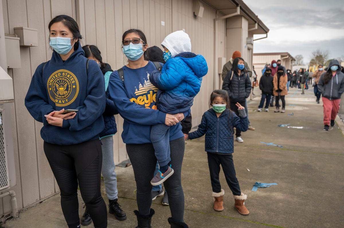 Heile Gantan, a UC Irvine student braved the cold morning on Monday, Jan. 3, 2022 to get a COVID-19 test at the La Familia Counseling Center in south Sacramento with her sister Theresa Gantan-Soliven, holding son Rowen Soliven, 3, as daughter Melody Soliven, 5, stands nearby. Gantan-Soliven said her daughter Melody tested positive for COVID-19 in a rapid test and they wanted to make sure no one else in their family had it.
