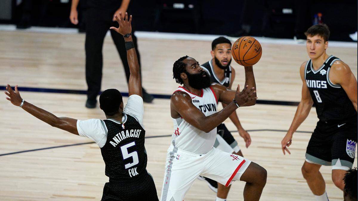 Houston Rockets’ James Harden (13), center, puts up a shot past Sacramento Kings’ De’Aaron Fox (5) during the first half of an NBA basketball game Sunday, Aug. 9, 2020, in Lake Buena Vista, Fla. (AP Photo/Ashley Landis, Pool)